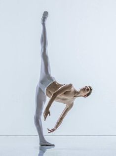 a man is doing a handstand on the floor in front of a white wall