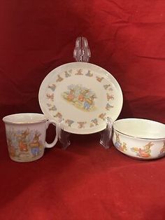 three cups and two saucers on a red tablecloth with the image of winnie the pooh