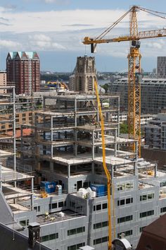 a large crane is on top of a building under construction in the middle of a city