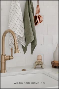 a kitchen sink with copper faucet and towels hanging on the wall