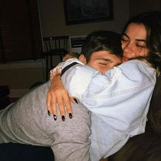 a woman is hugging a man on the couch