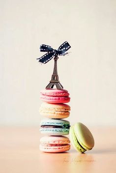 a stack of macaroons with a bow on top and the eiffel tower in the background