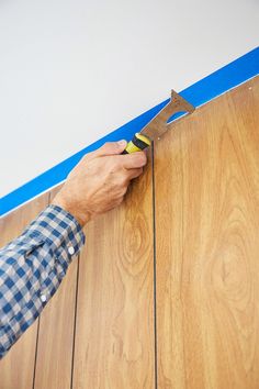 a man with a pair of pliers in his hand working on wood flooring