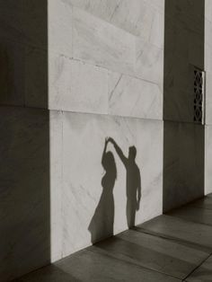 a shadow of a person reaching up to the side of a building