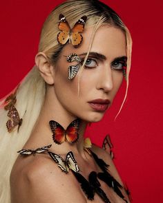 a woman with long blonde hair and butterflies on her face is posing for the camera