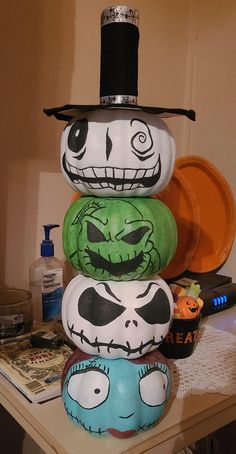 a stack of halloween pumpkins with faces painted on them, sitting on a table