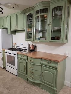 a kitchen with green cabinets and white appliances