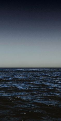 an airplane is flying over the ocean on a clear day with dark blue skies above