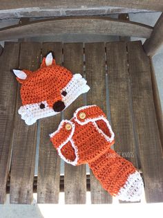 two crocheted fox mitts sitting on top of a wooden chair next to each other