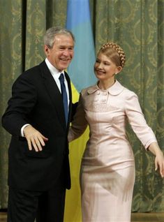 a man and woman standing next to each other in front of a curtained wall