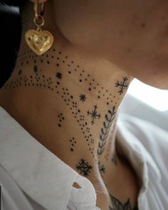 a woman's neck with stars and hearts tattooed on her left side, while she is wearing a white shirt