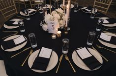 the table is set with black and white linens, silverware, and candles