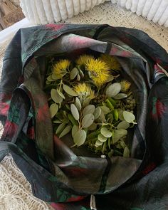 a bunch of flowers that are in a bag on a table with some cloth around it