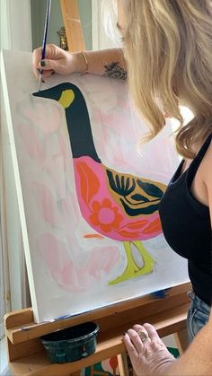 a woman is painting a duck on an easel