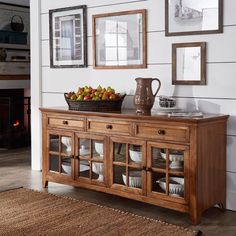 a wooden buffet table topped with fruit on top of a hard wood floor next to a fireplace