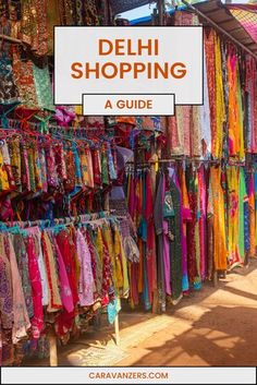 an outdoor market with colorful fabrics and scarves for sale in delhi, india text overlay reads delhi shopping a guide