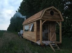 a woman sitting on the back of a truck in front of a small wooden cabin