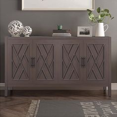 a gray sideboard with two vases on it in front of a painting and rug