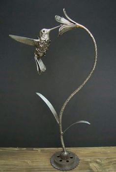 a metal bird sculpture on top of a wooden table