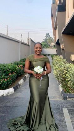 a woman in a long green dress holding a bouquet