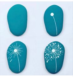 three painted rocks with dandelions on them, one blue and the other white