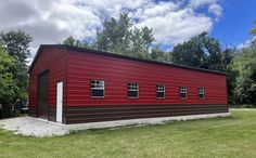 a large red building sitting on top of a lush green field next to trees and grass