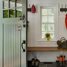 the inside of a house with shoes and umbrellas hanging from hooks on the wall