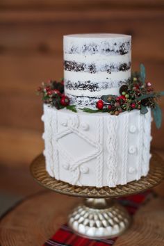 a three tiered cake decorated with berries and greenery