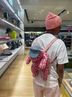 a man with a pink hat is holding a stuffed animal in a store display case