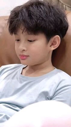 a young boy sitting on top of a brown couch