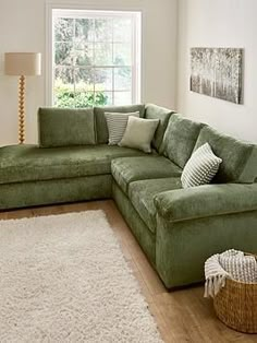 a living room with a large green sectional couch and white rugs on the floor