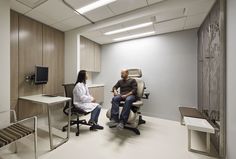 an office with a chair, desk and television on the wall in front of it