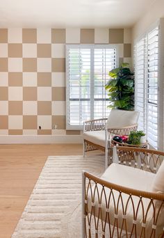 a living room with two chairs and a rug in front of the window that has shutters on both sides