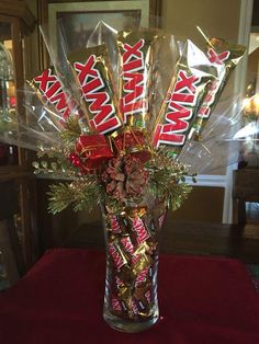 a glass vase filled with candy bars and christmas decorations