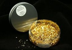 a jar filled with gold glitter sitting on top of a black table next to a metal container