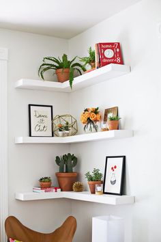 three white shelves with plants and pictures on them