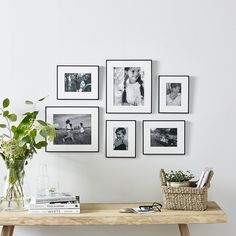 a wooden table topped with pictures next to a vase filled with green plants and flowers