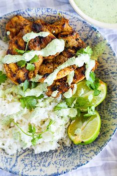 a blue and white plate topped with rice, chicken and cilantro garnish