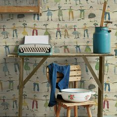 a table with a typewriter and bowl on it in front of a wallpapered background