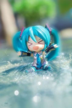 an action figure in the water with blue hair and long bangs, wearing a suit