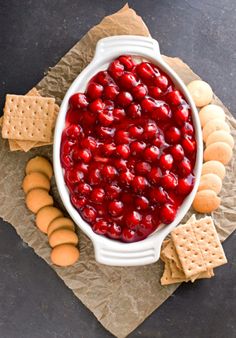 a white bowl filled with cranberry sauce surrounded by crackers