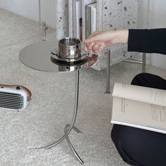 a person sitting on the floor next to a table with a book and an old radio