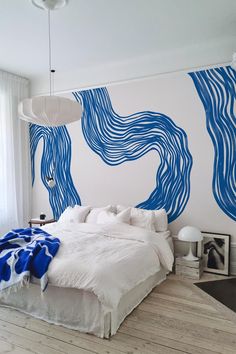 a large bed sitting in a bedroom next to a wall with blue waves painted on it