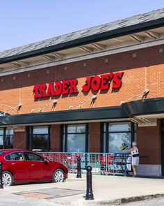 a red car parked in front of a trader joe's