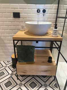 a white bowl sink sitting on top of a wooden shelf next to a black and white tiled wall