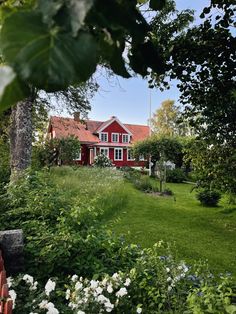 a red house surrounded by trees and flowers