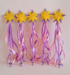 four purple and yellow streamers with flowers on them are lined up against a white wall