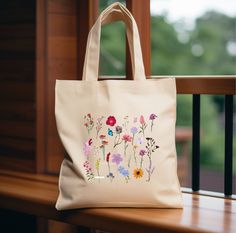 a bag with flowers painted on it sitting on a window sill next to a railing