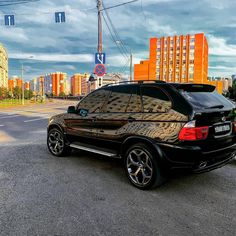 a black car is parked on the side of the road in front of tall buildings