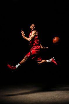 a basketball player is in the air with his foot up as he dribbles a ball